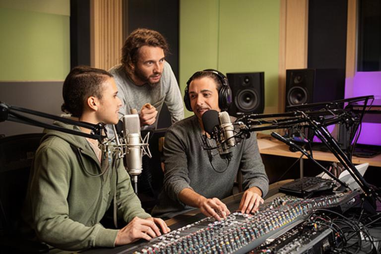 Audioteam werkt samen aan een podcastmix in de studio met mengtafel en microfoons