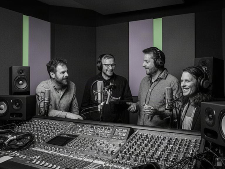 Vier audio professionals rond een mengtafel in een geluidsdichte podcaststudio in Etten-Leur
